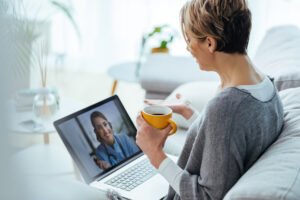 Laptop aberto em uma, mostrando uma sessão de terapia online com uma psicóloga online em chamada de vídeo, em um ambiente acolhedor.
